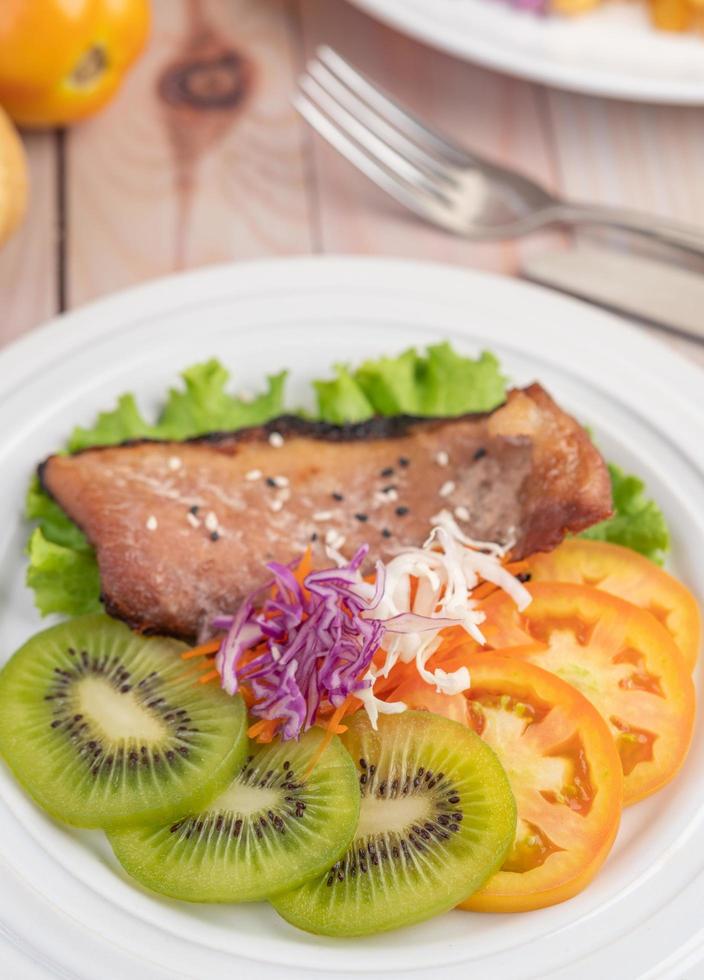 bife de peixe com batata frita, frutas e vegetais foto