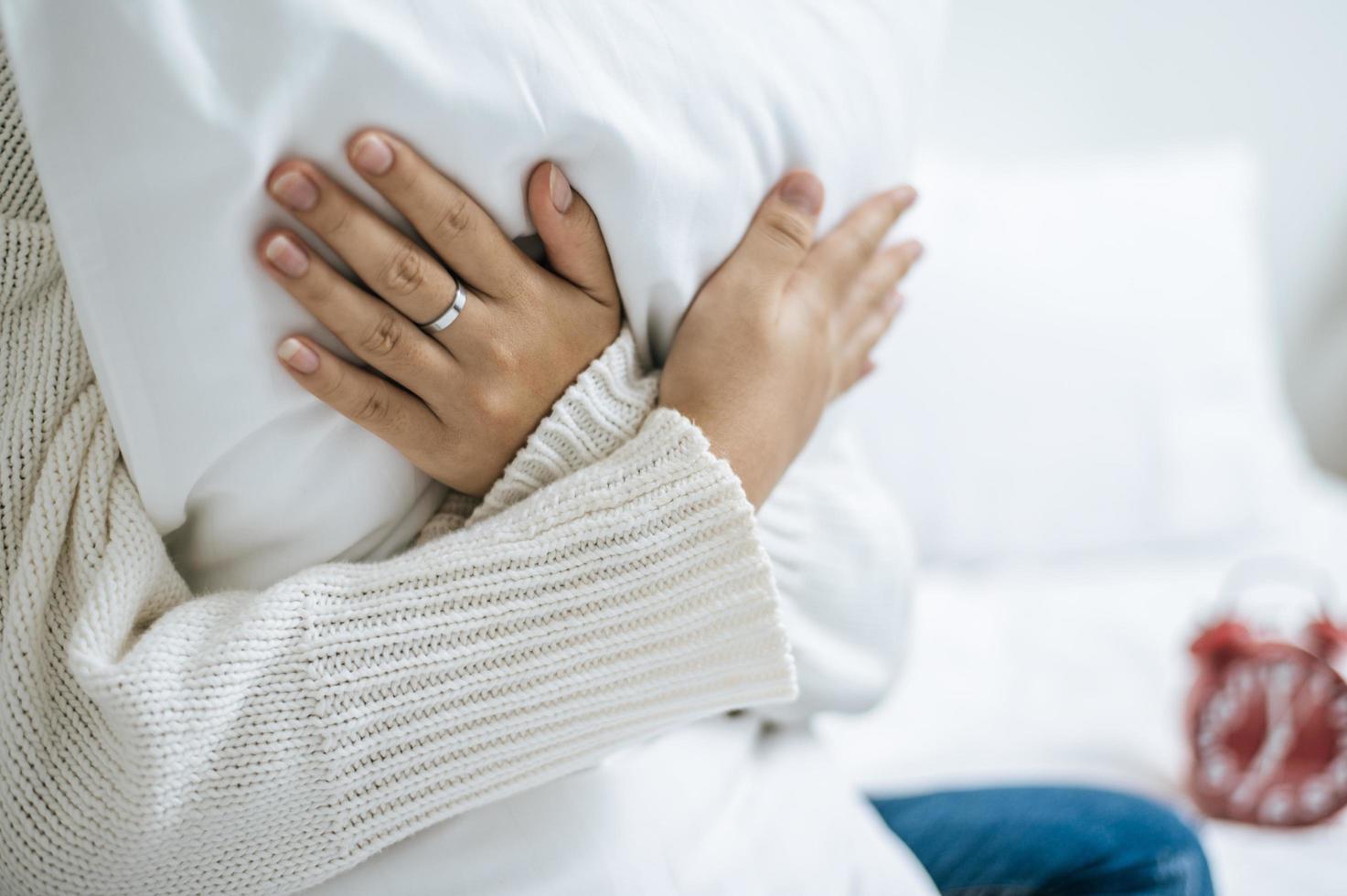 pessoa abraçando um travesseiro branco na cama foto