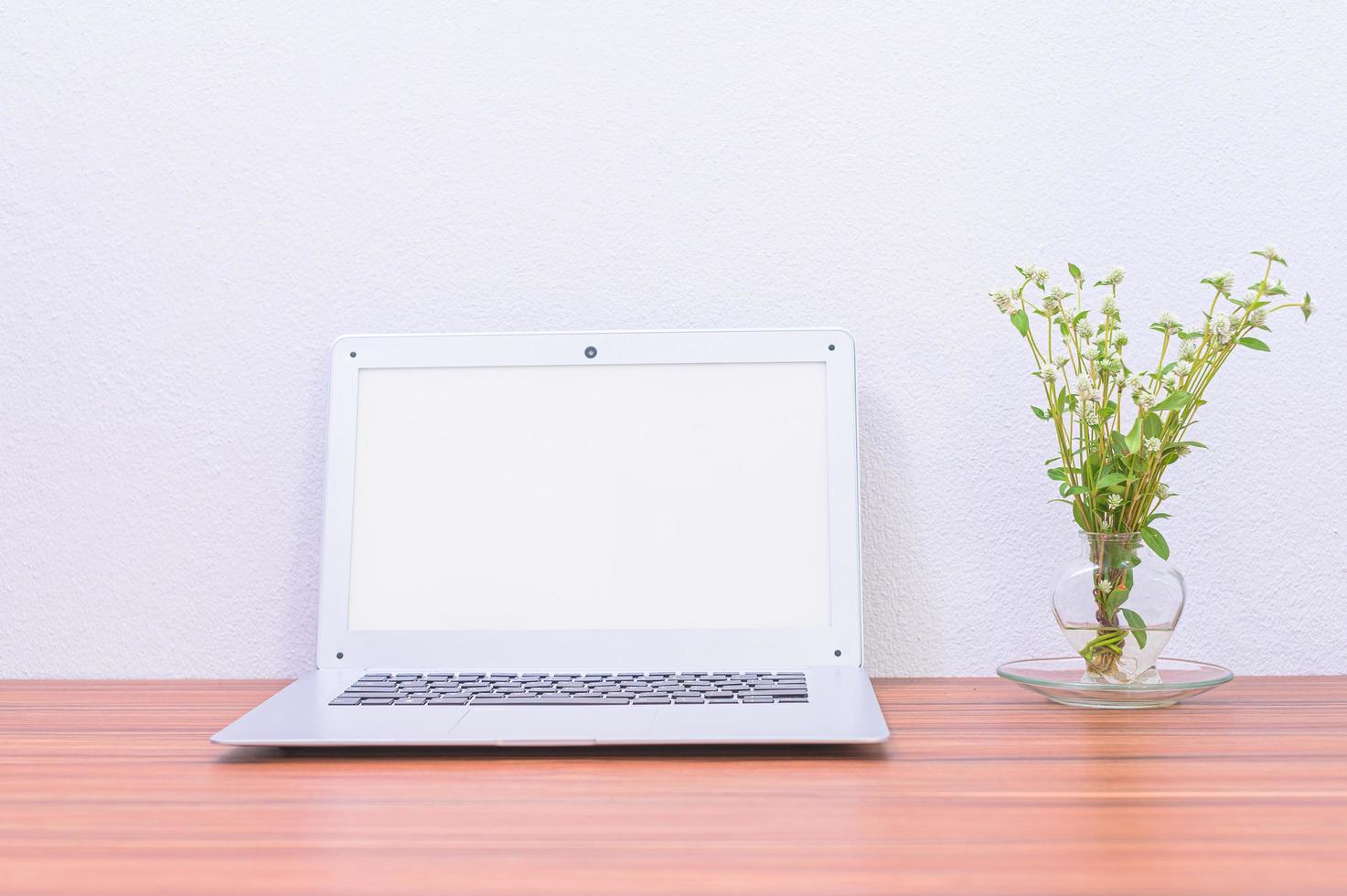 laptop e flor na mesa foto