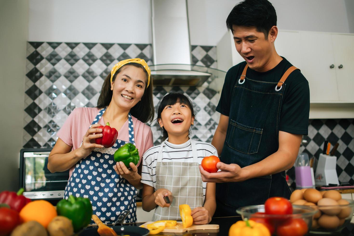 família feliz cortando vegetais juntos na cozinha foto