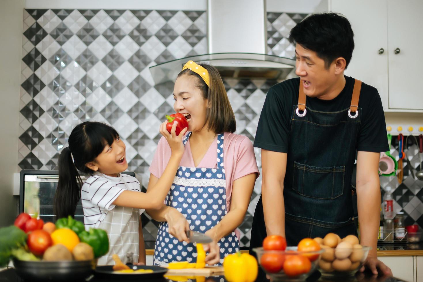 família feliz cortando vegetais juntos na cozinha foto