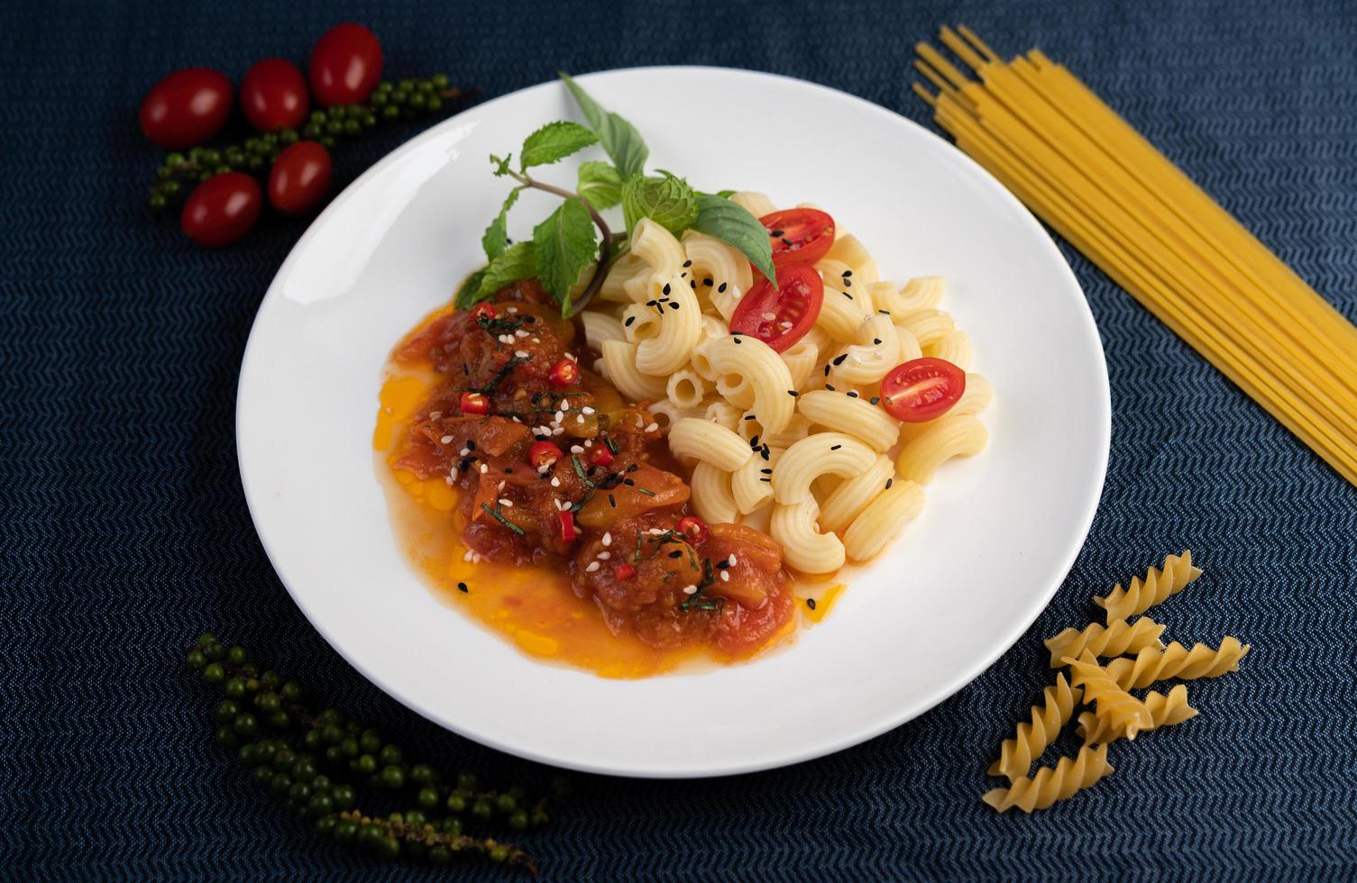 macarrão frito com tomate, pimenta, sementes de pimenta e manjericão foto