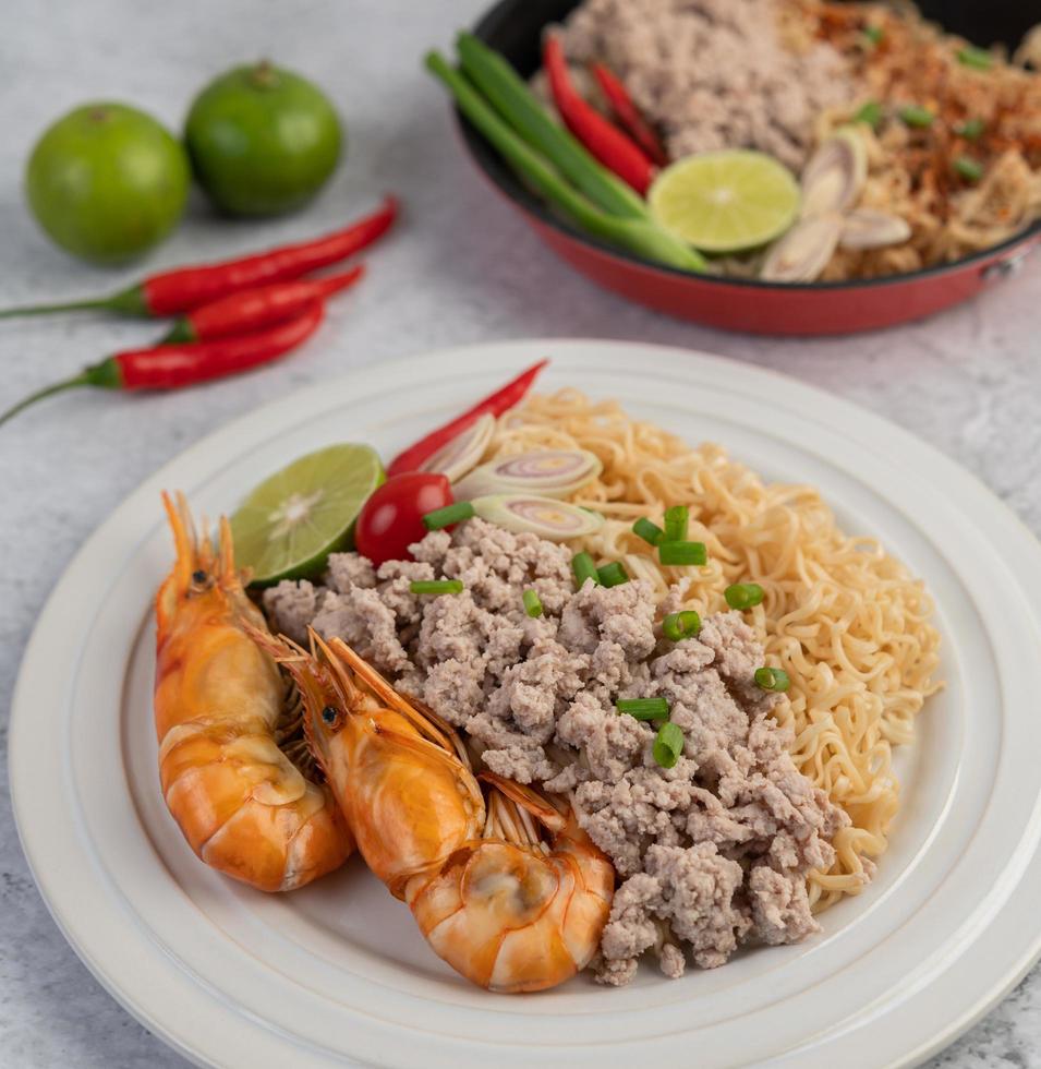 macarrão e camarão em um prato branco foto