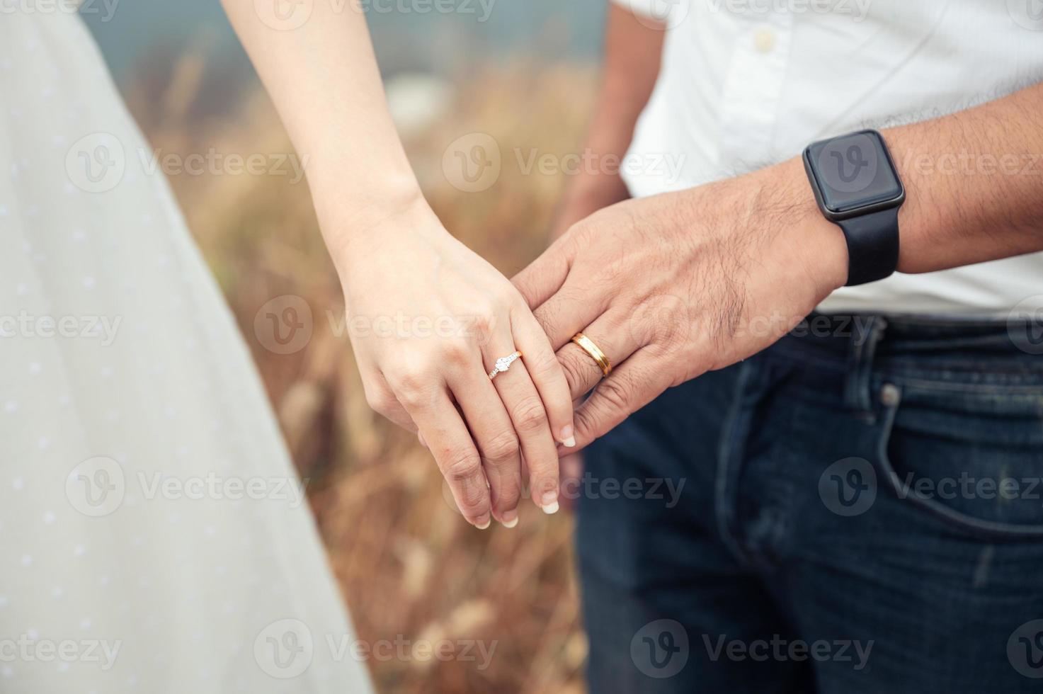 noiva e noivo em pé de mãos dadas com anel de casamento na floresta antes do dia do casamento. vestido de noiva, casal foto
