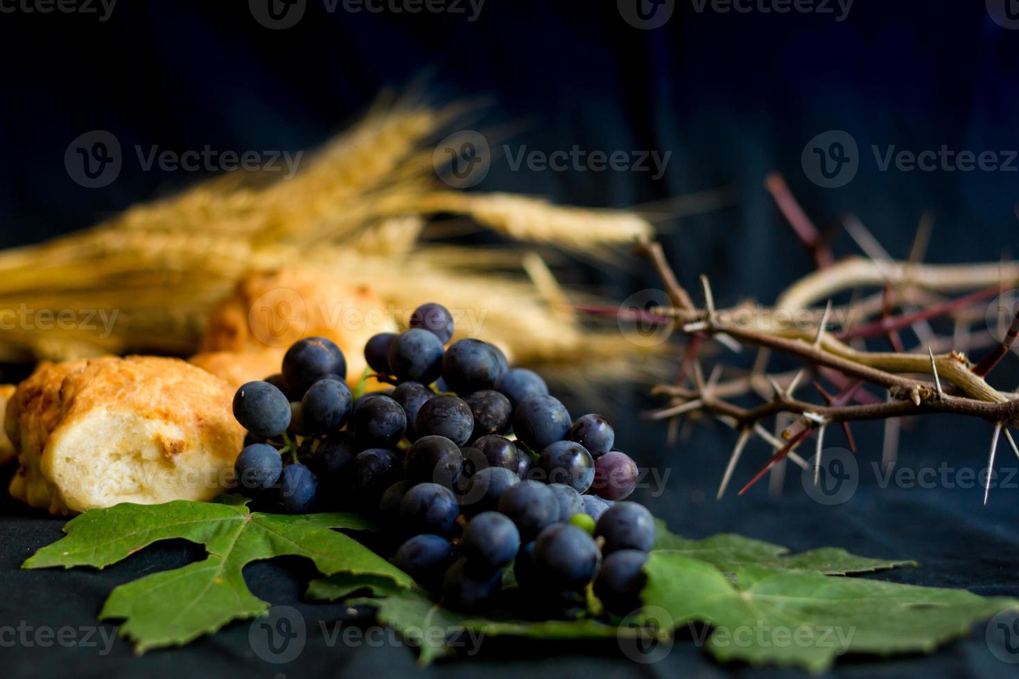 pão de uvas de trigo e coroa de espinhos em fundo preto como um símbolo do cristianismo foto