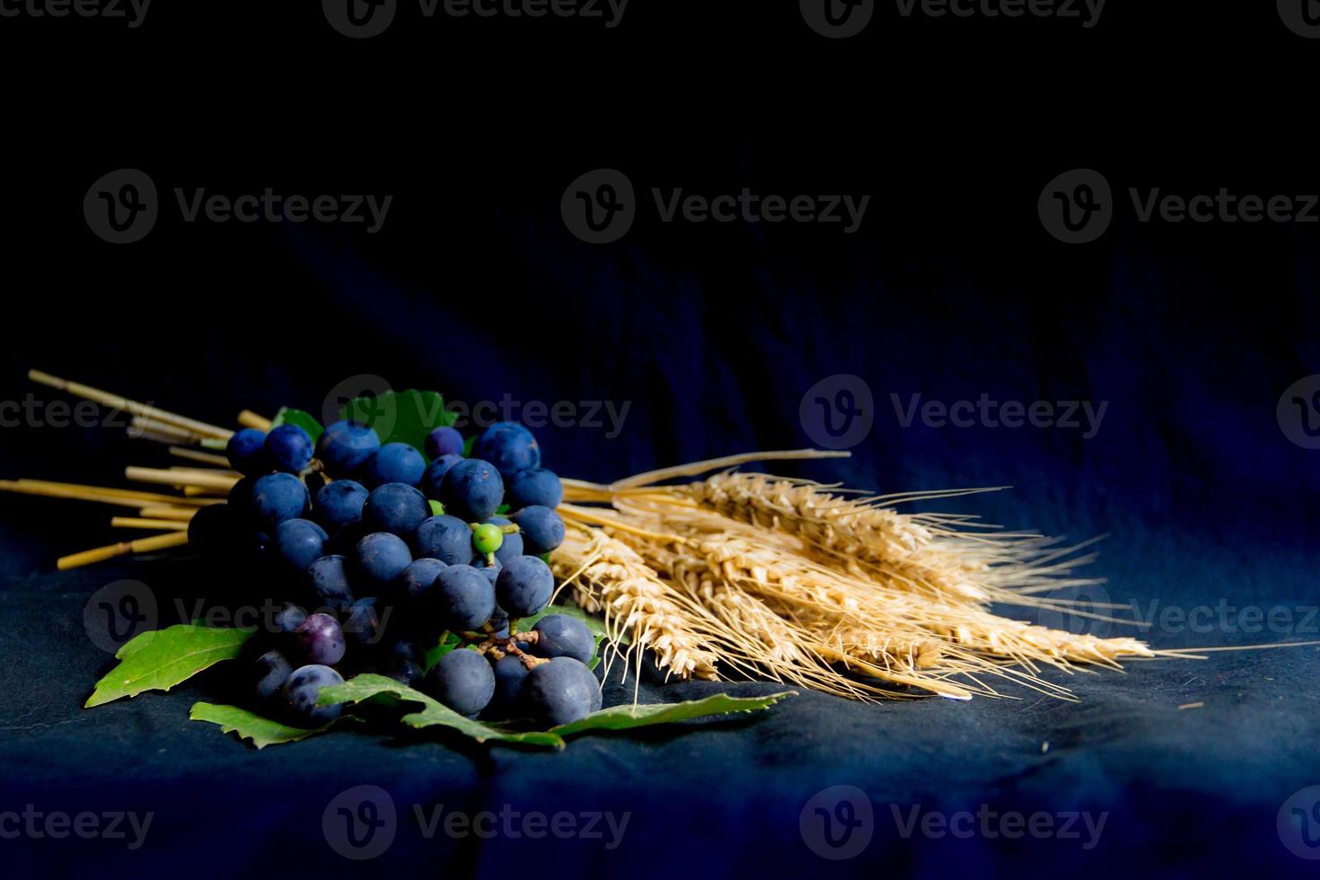 pão de uvas de trigo e coroa de espinhos em fundo preto como um símbolo do cristianismo foto