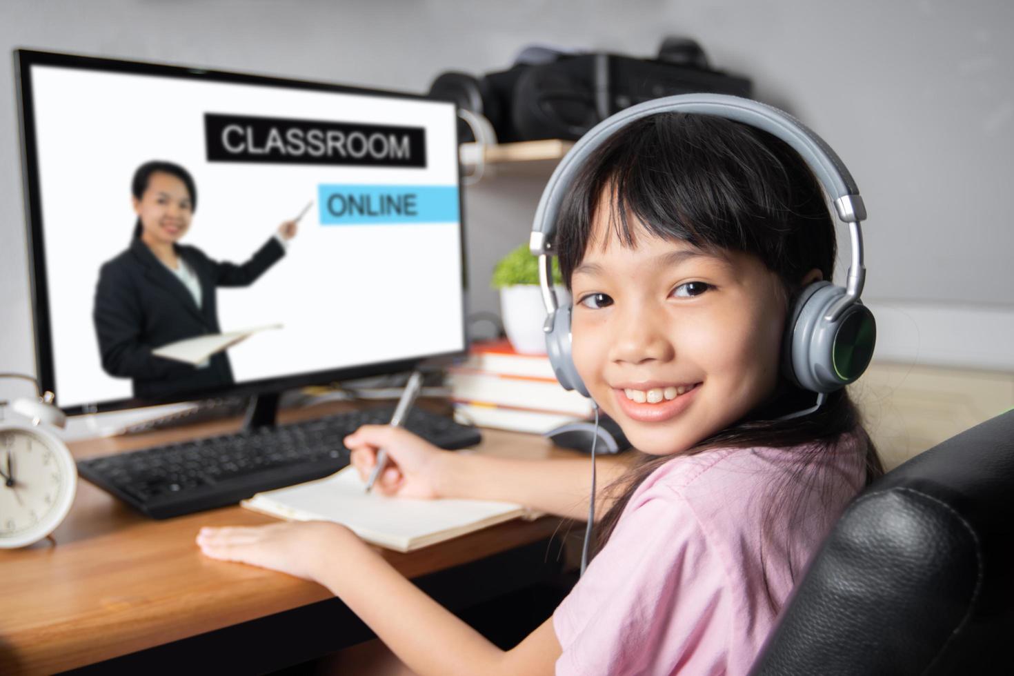 sala de aula e educação on-line e rede escolar, aluna jovem asiática ou tailandesa aprendendo no computador desktop no professor em casa ensinando como tv digital digital durante coronavírus ou doença covid 19 foto