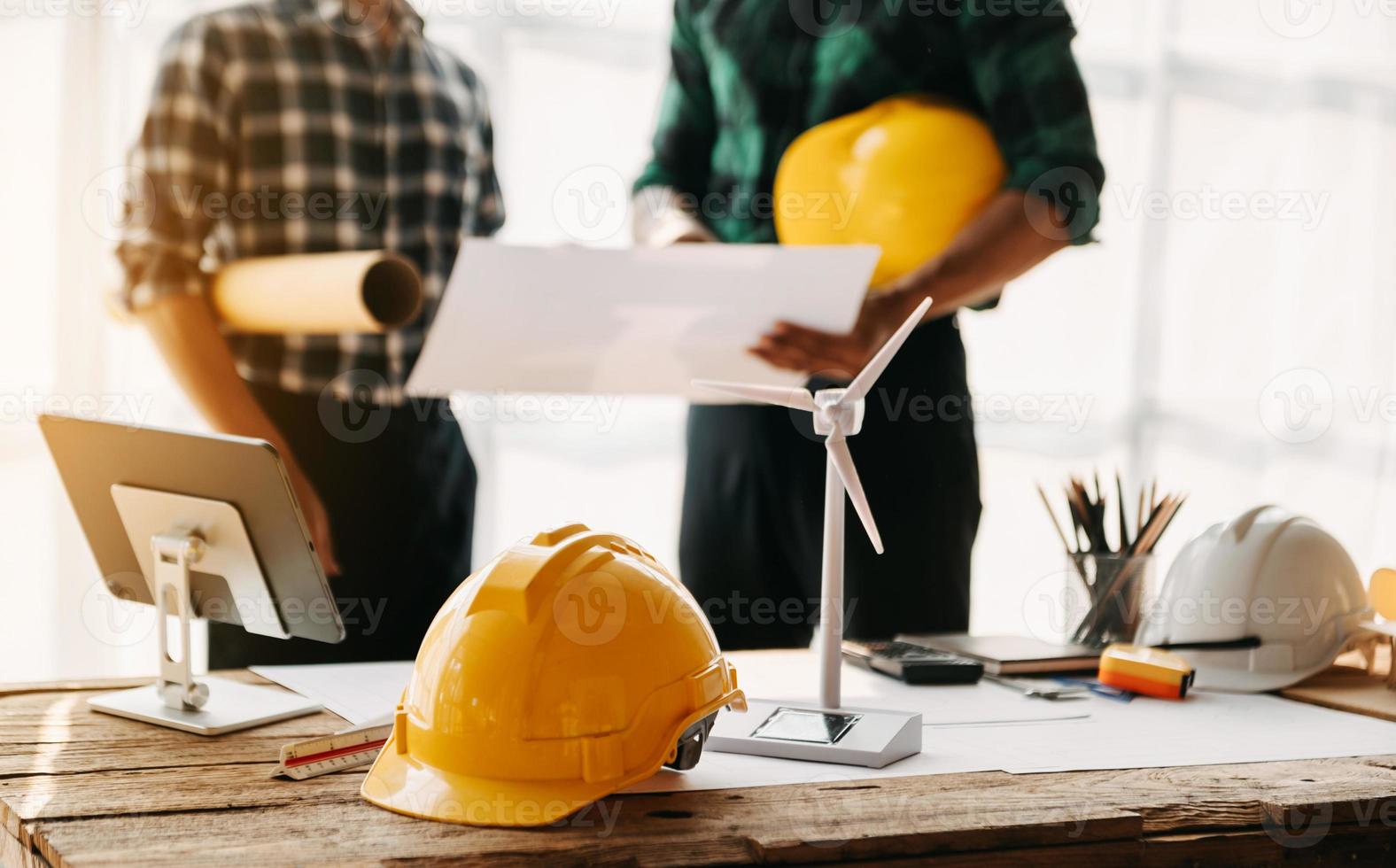 mesa de engenheiro com papel de objeto e tablet com trabalho em equipe de engenheiro embaçado, trabalhando duro para consultar sobre seu projeto de construção. foto