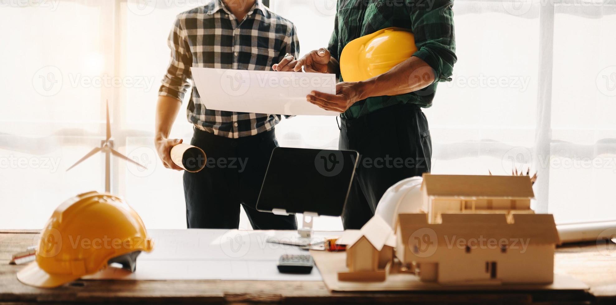 mesa de engenheiro com papel de objeto e tablet com trabalho em equipe de engenheiro embaçado, trabalhando duro para consultar sobre seu projeto de construção. foto