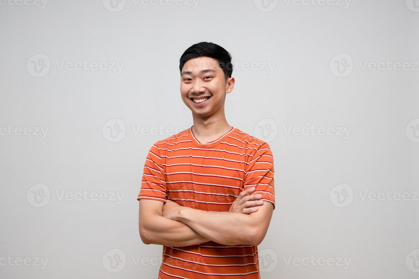 homem asiático positivo camisa listrada felicidade sorriso em pé de braços cruzados isolado foto