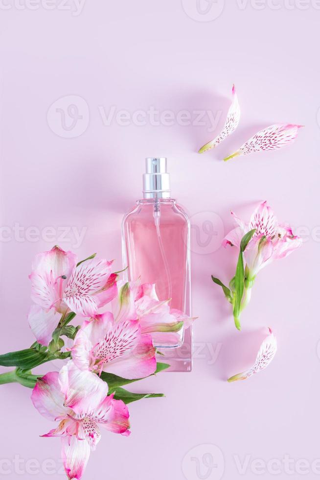 um frasco chique de perfume feminino ou spray cosmético em um fundo vertical rosa entre as delicadas flores da astromeria. apresentação aromática. foto