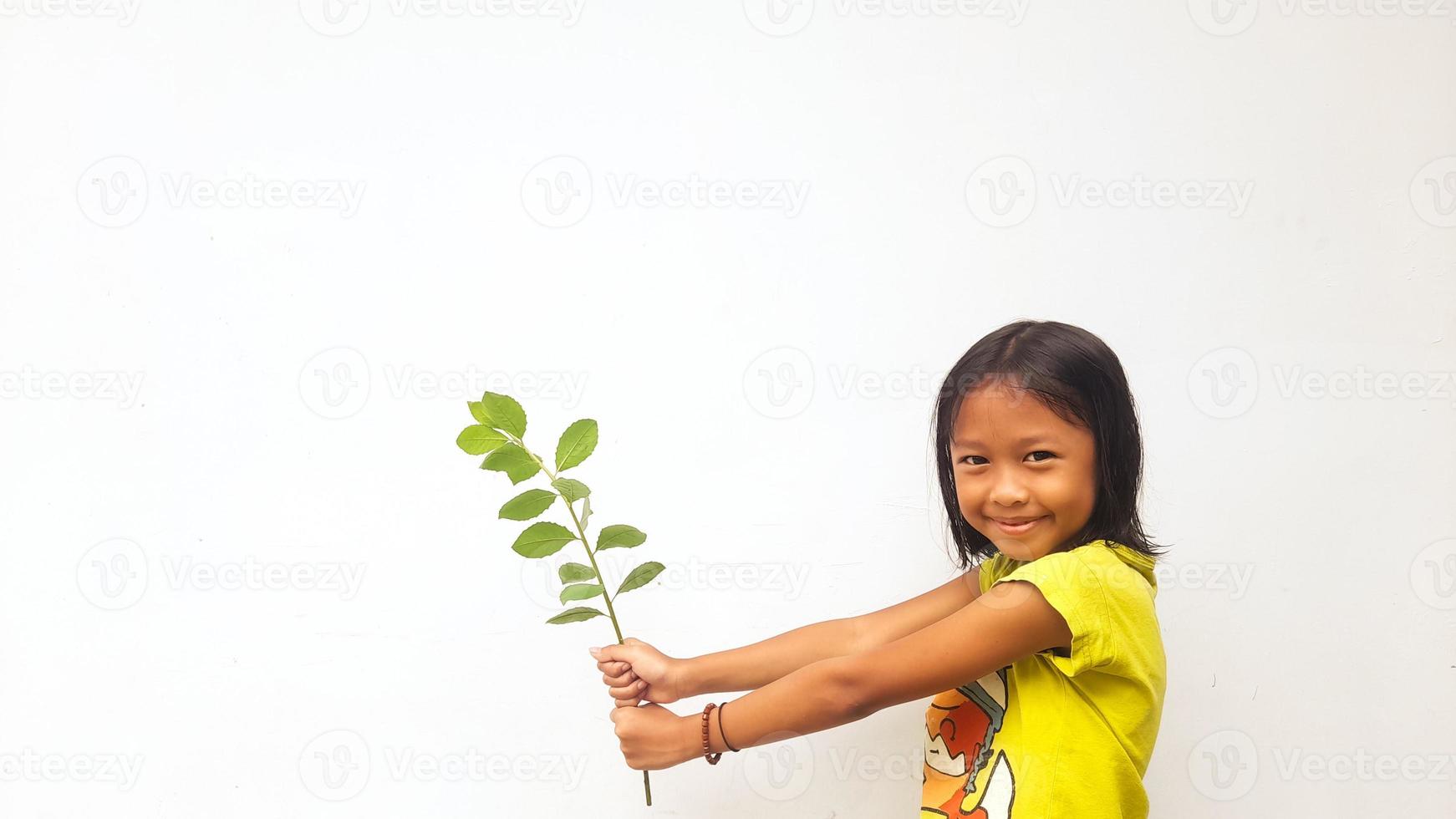 menina segurando planta jovem. folhas verdes. conceito de ecologia. fundo de cor clara. foto