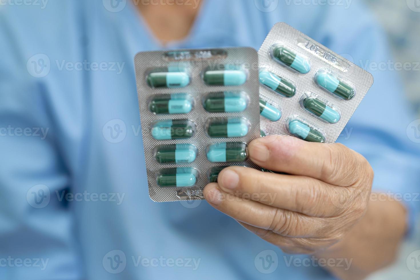 paciente asiático sênior ou idosa senhora segurando comprimidos da cápsula de antibióticos em embalagem blister para paciente de infecção de tratamento no hospital, conceito de farmácia farmácia. foto