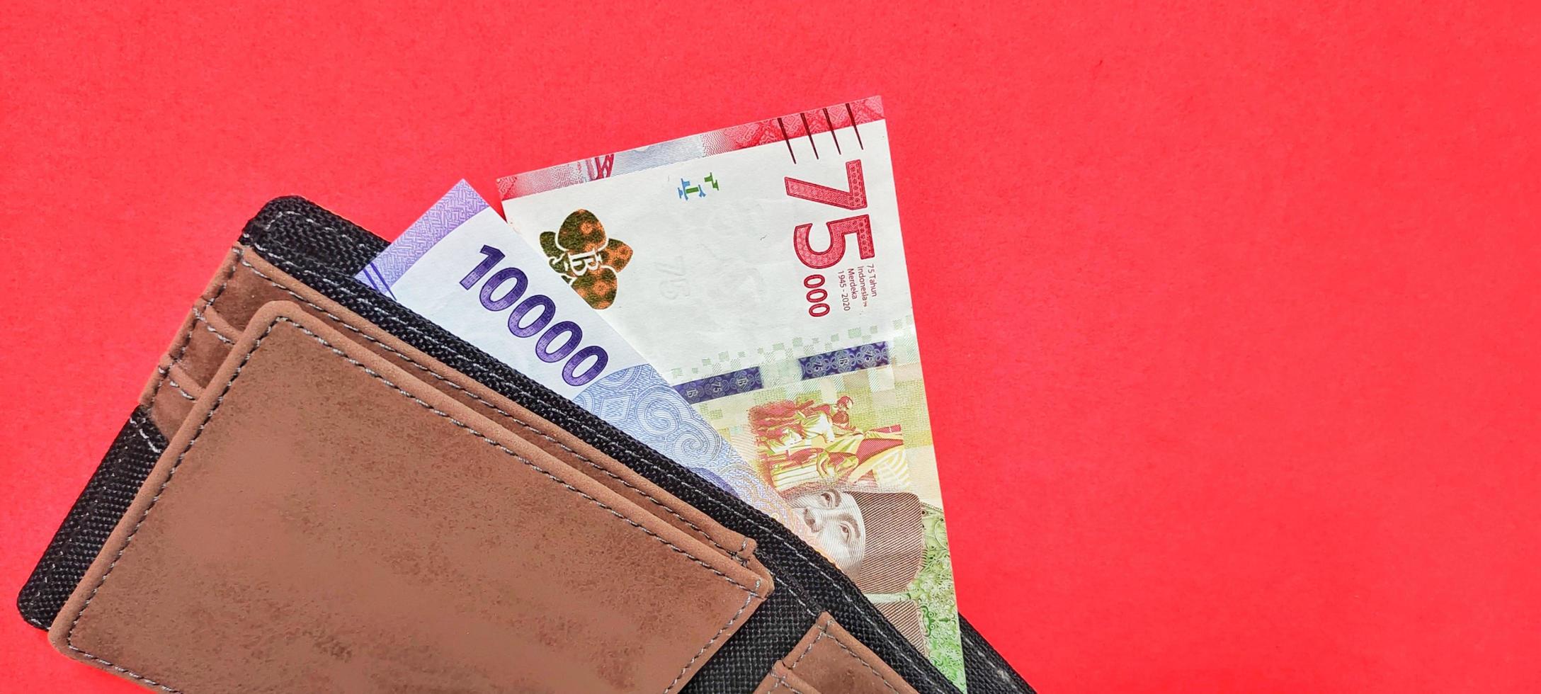 dinheiro novo indonésio na carteira, isolado em um fundo vermelho. foto