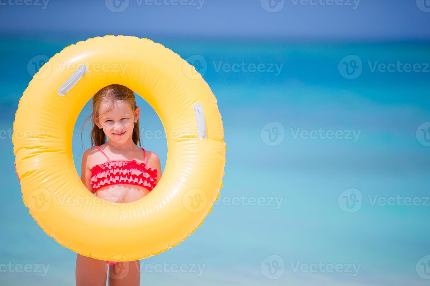 menina adorável com círculo de borracha inflável durante as férias na praia foto