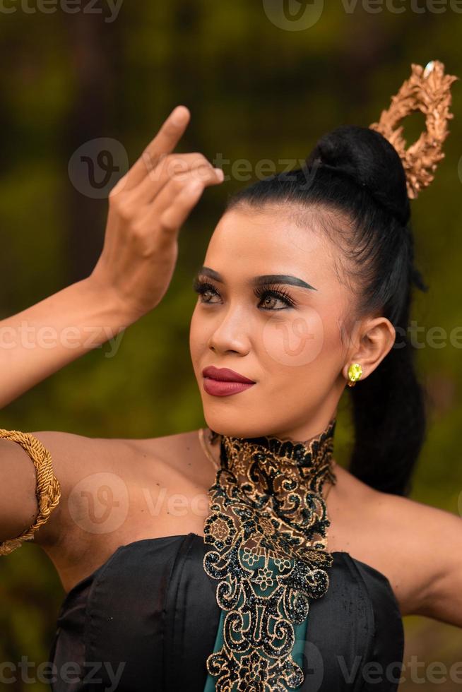 retrato de uma mulher balinesa com bela maquiagem e cabelo preto amarrado em uma expressão facial corajosa foto