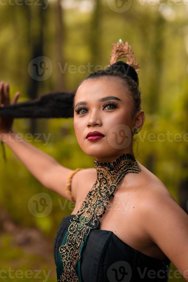 linda mulher asiática em maquiagem com cabelo preto e batom vermelho usando joias de ouro durante a apresentação de dança foto