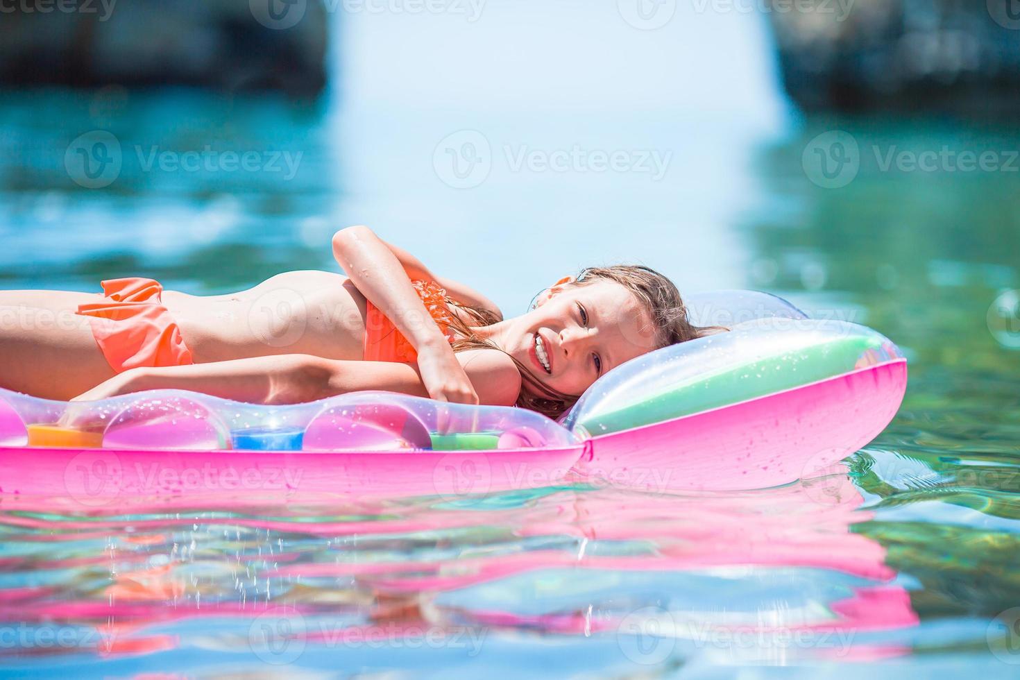 menina adorável no colchão de ar inflável no mar foto