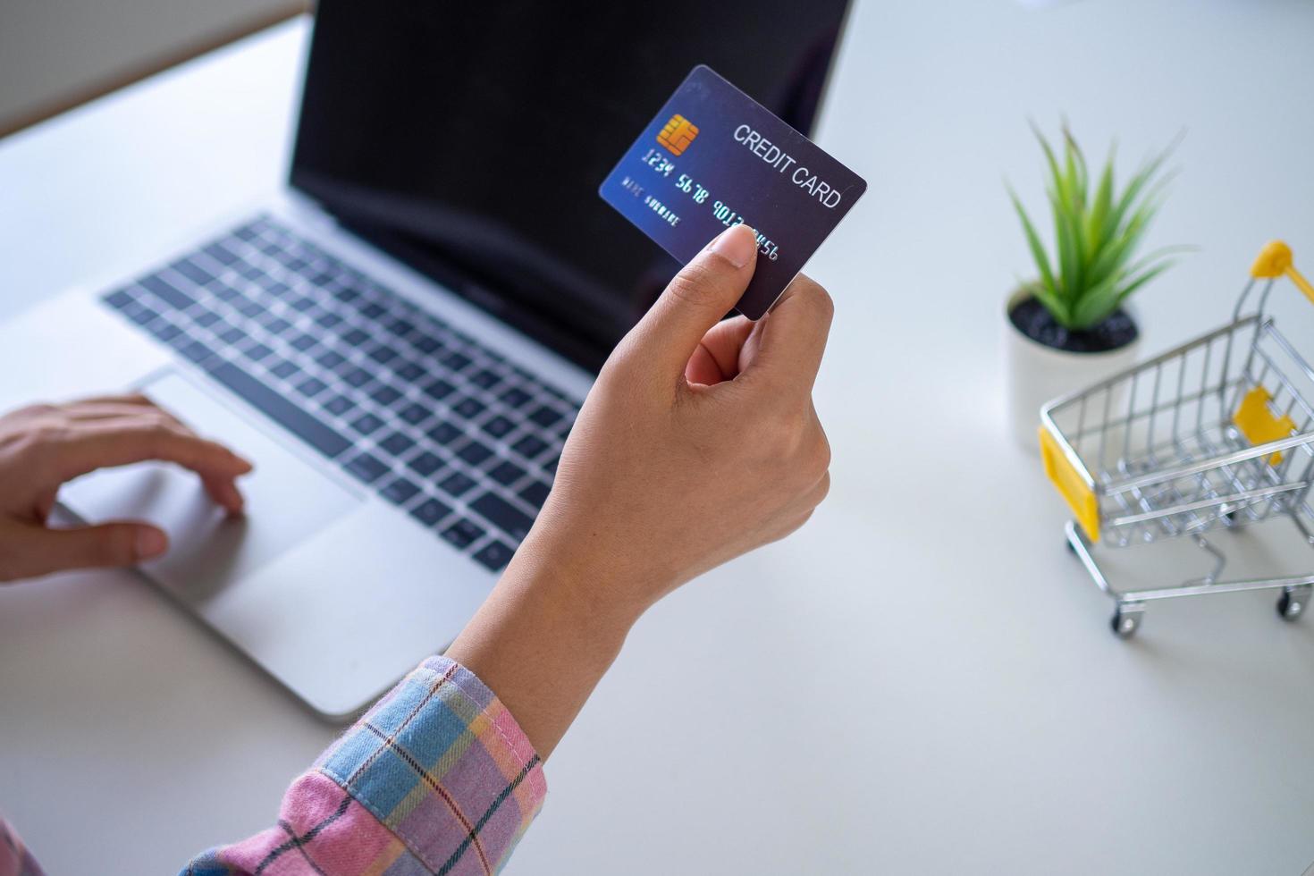 mulher usa cartão de crédito para compras e pagamento on-line no computador. conceito de compras online. foto