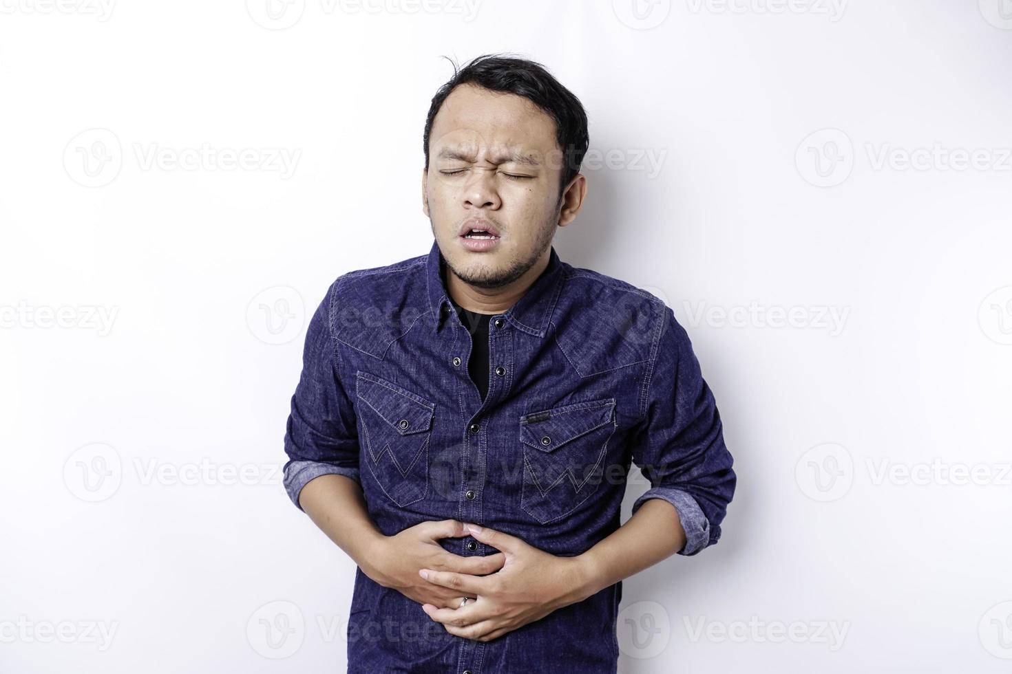 foto de jovem indisposto doente segurando a mão no estômago sofre dor isolada no fundo branco