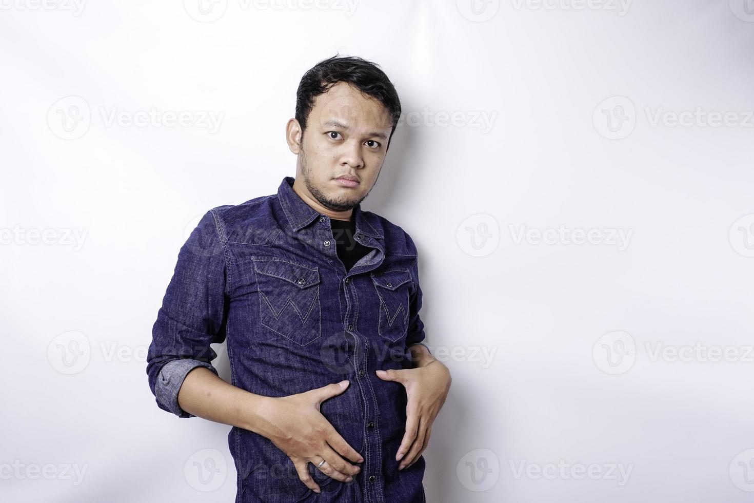 um retrato de homem gordo asiático inseguro está segurando a gordura na barriga foto