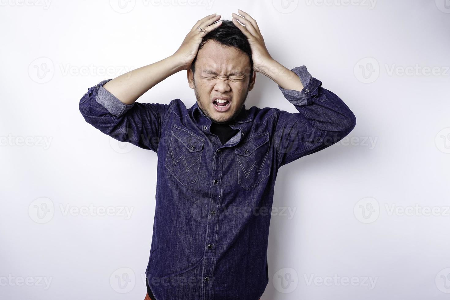 um retrato de um homem asiático vestindo uma camisa azul isolada por um fundo branco parece deprimido foto