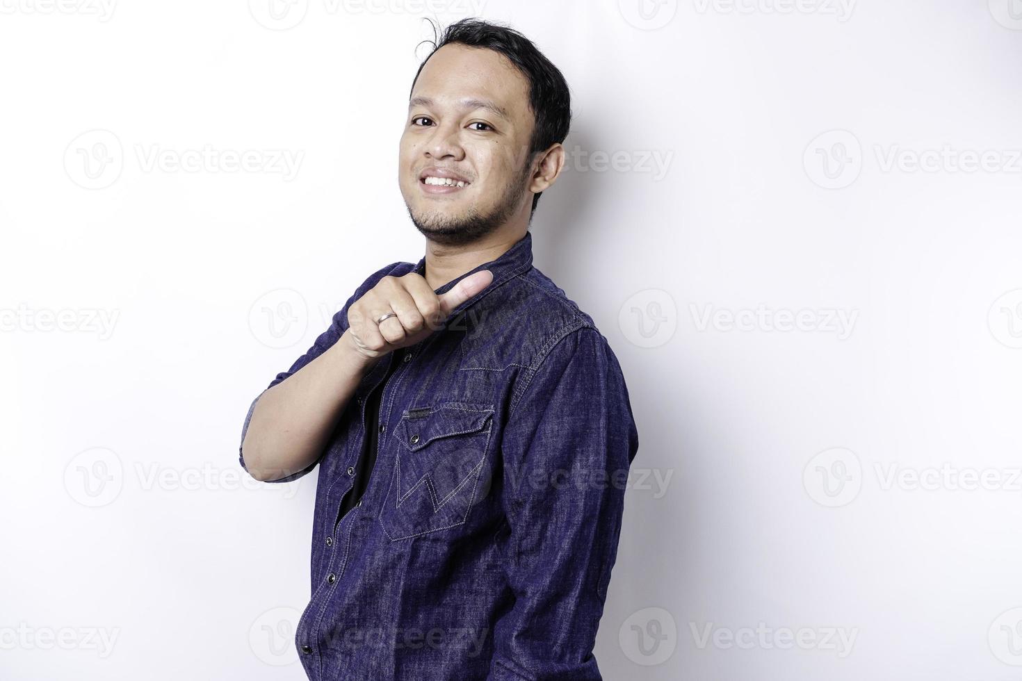 homem asiático animado vestindo camisa azul apontando para o espaço da cópia ao lado dele, isolado pelo fundo branco foto