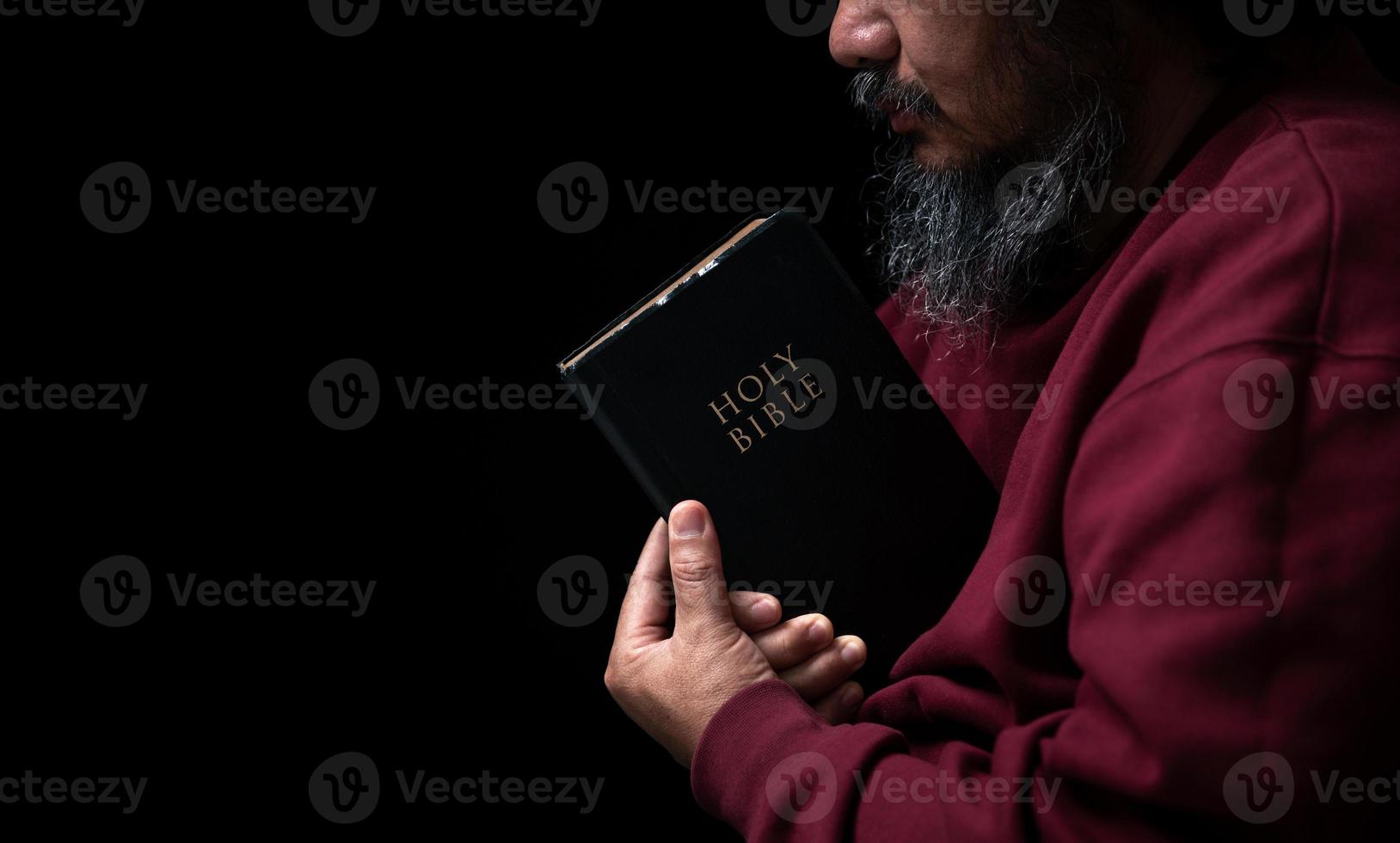 mãos postas em oração em uma bíblia sagrada no conceito de igreja para fé, espiritualidade e religião, homem orando pela manhã. mão de homem com a Bíblia rezando. pessoa cristã que tem fé em jesus adora no escuro. foto