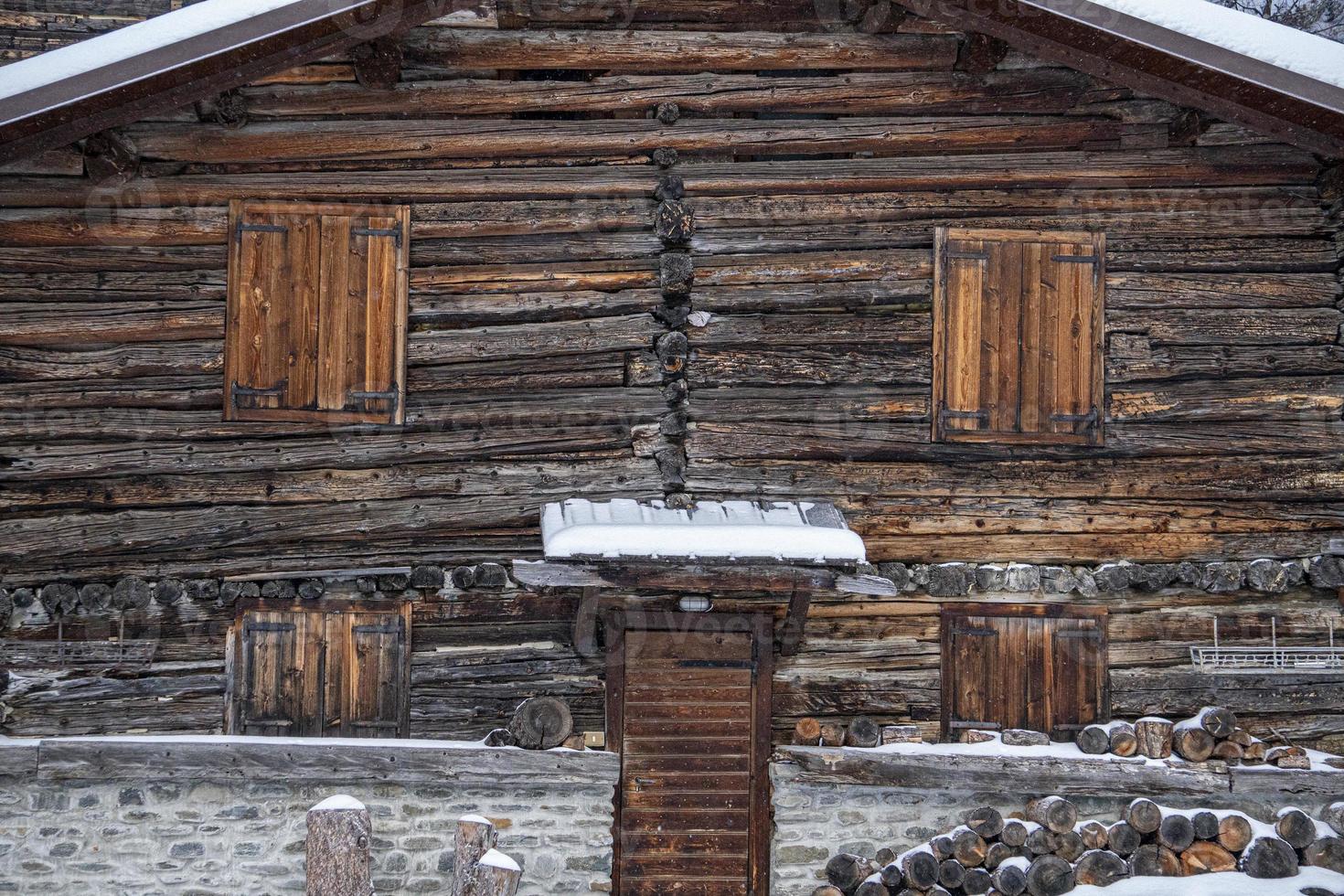cabana de madeira coberta pela neve nas dolomitas foto