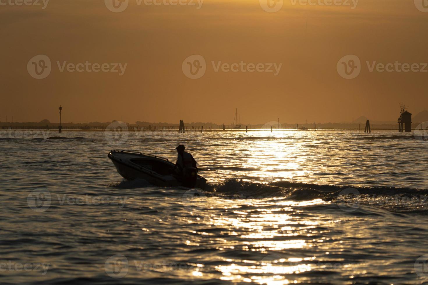 silhueta de pescador ao pôr do sol na lagoa de veneza porto de chioggia de um barco foto