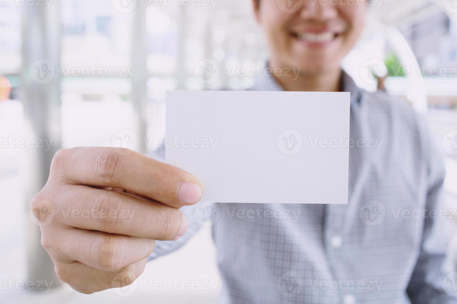 homem de negócios na mão mostra o cartão branco em branco simulado com cantos arredondados. modelo de maquete de cartão de chamada simples segurando o braço. frente de exibição de cartão de crédito de plástico. conceito de marca de negócios. foto