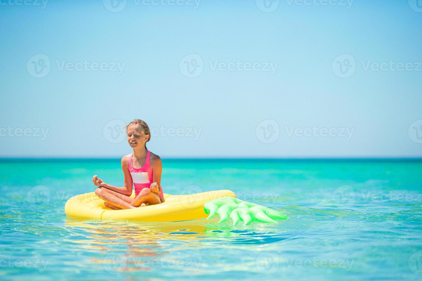 menina adorável no colchão de ar inflável no mar foto