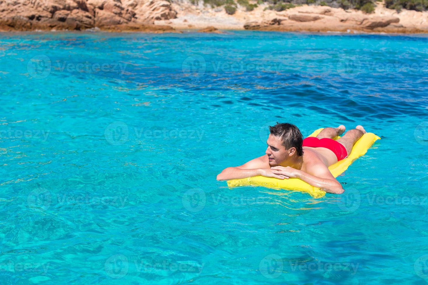 jovem relaxante no colchão inflável no mar foto