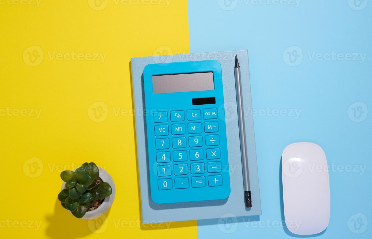 bloco de notas azul, calculadora e lápis de madeira sobre um fundo azul foto