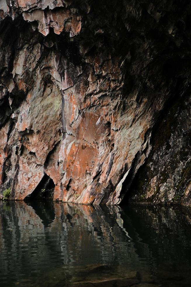 formação de rocha marrom e cinza ao lado do corpo d'água durante o dia foto