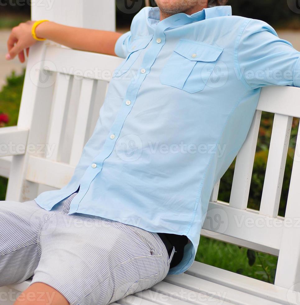 retrato de um jovem relaxando no banco do parque foto