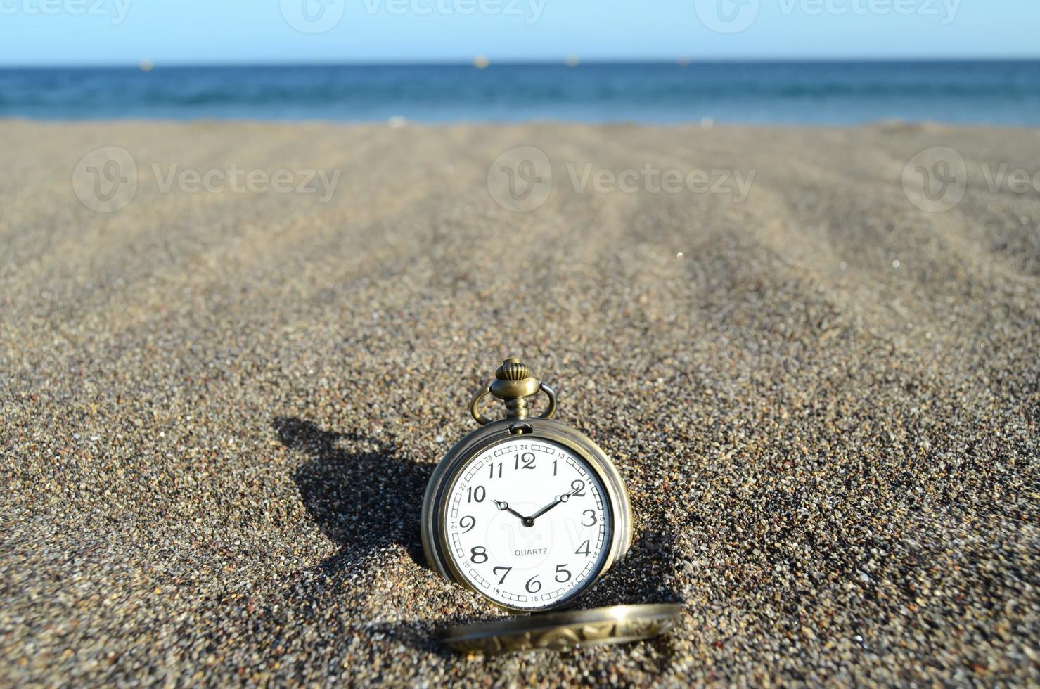 relógio de bolso na areia foto