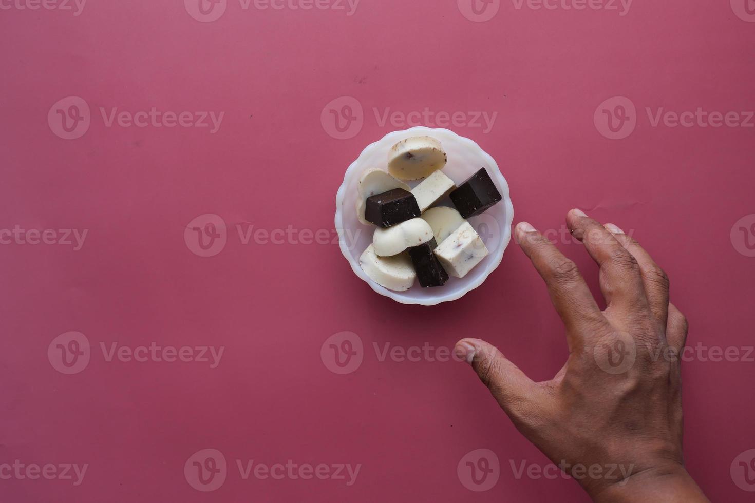 alcance de mão para chocolate amargo em um prato foto