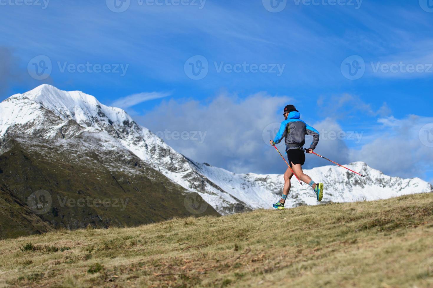 corrida de montanha de resistência. um homem com paus ladeira abaixo foto