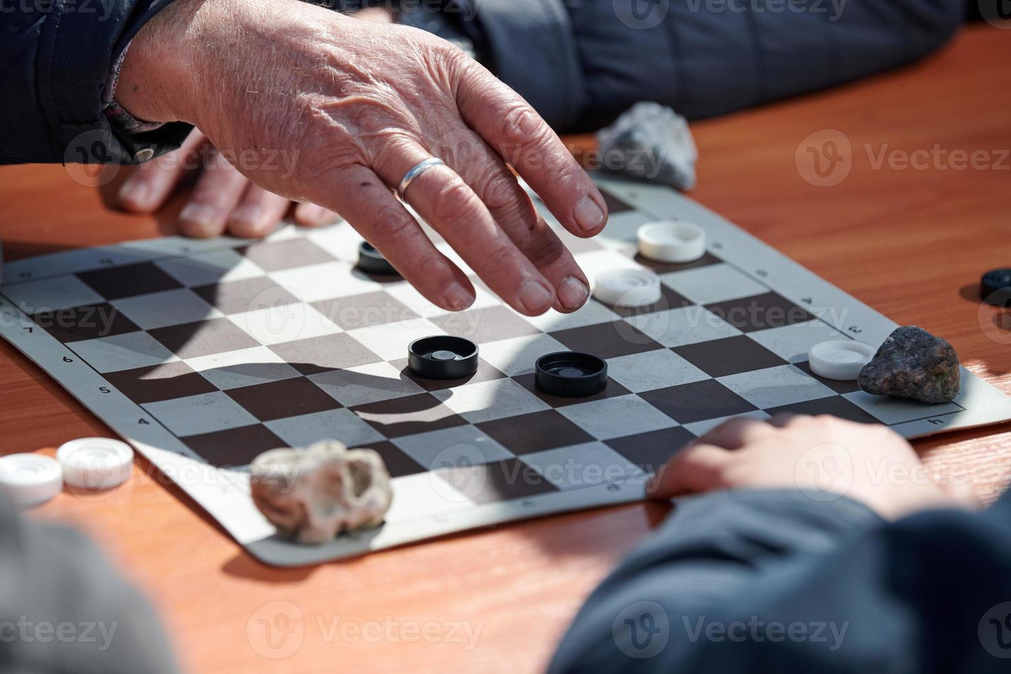 Torneio de damas ao ar livre no tabuleiro de damas de papel na mesa fechar  as mãos dos jogadores