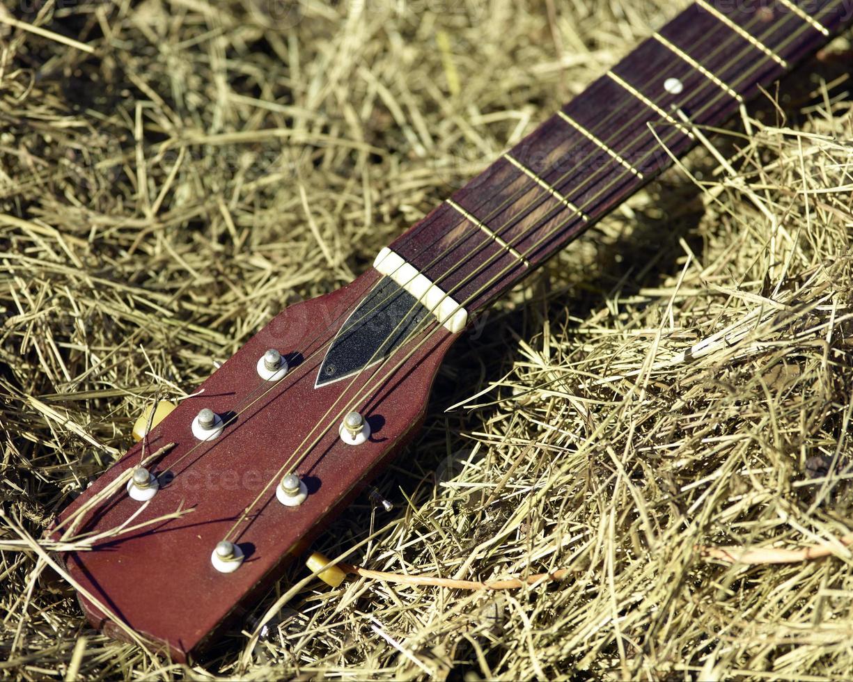 uma velha guitarra deitada em um fardo de feno foto