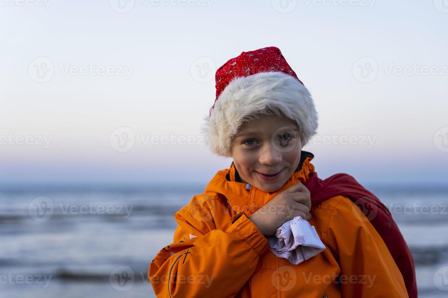 retrato de um menino bonito em um boné de st. nicholas, com um saco de presentes de natal e ano novo foto