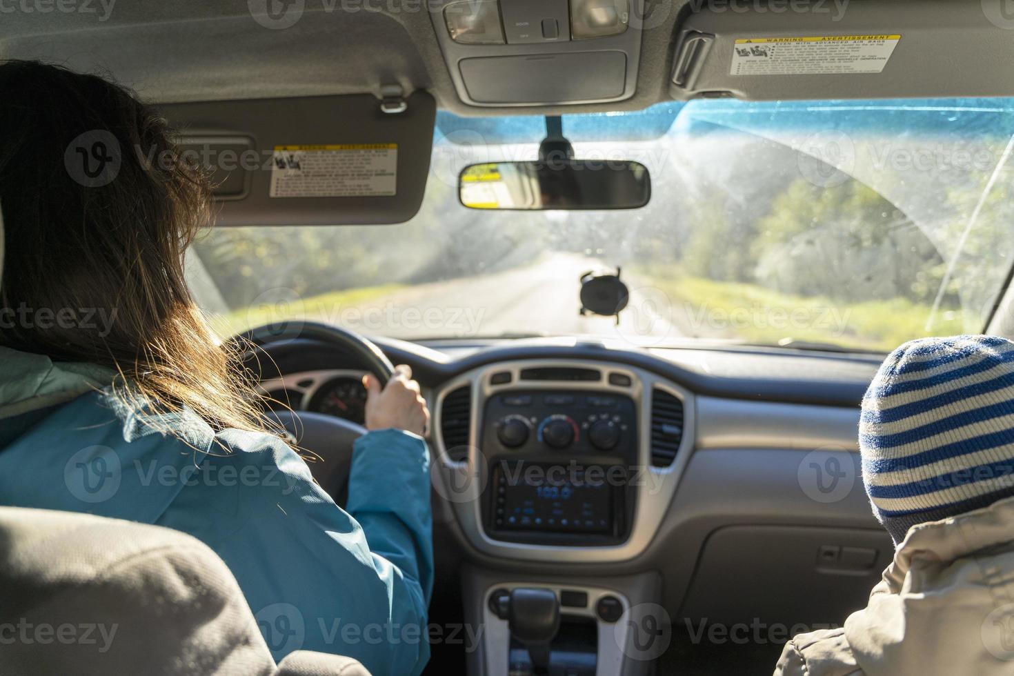 uma mulher dirigindo um carro com uma criança no banco do passageiro, uma jovem dirigindo seu carro, uma visão interna foto