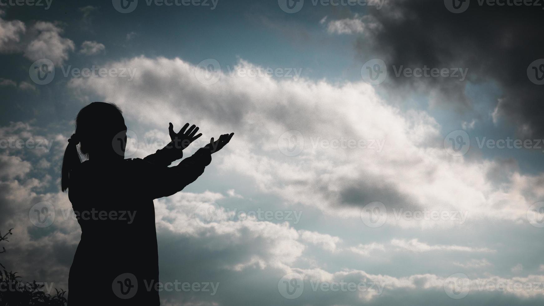 A religião de cristo e o cristianismo adoram ou rezam concept.silhouette da mulher católica cristã estão orando a deus no céu escuro. pessoa de oração mão no fundo da natureza. menina acredita e fé em jesus foto