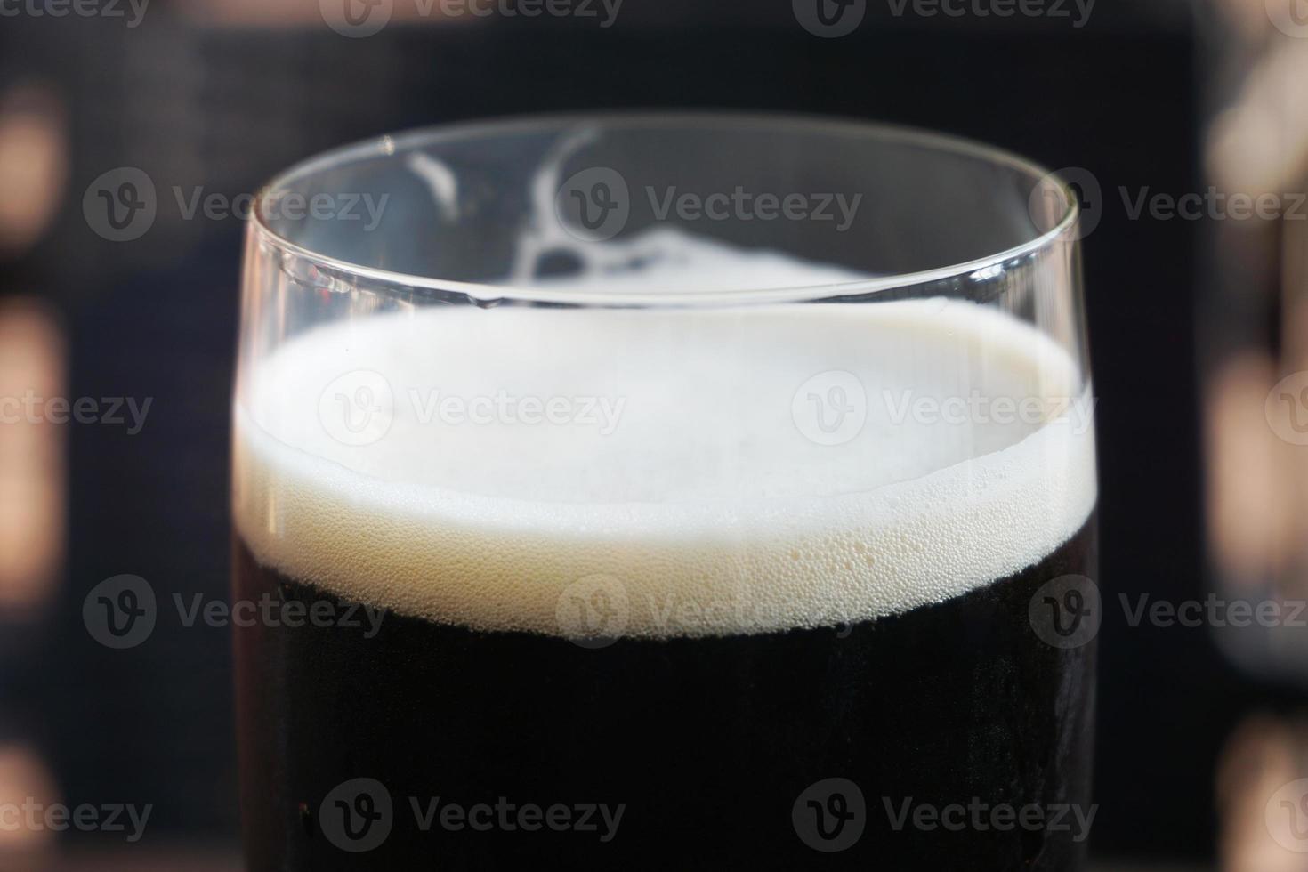 copo de cerveja escura, fundo desfocado foto