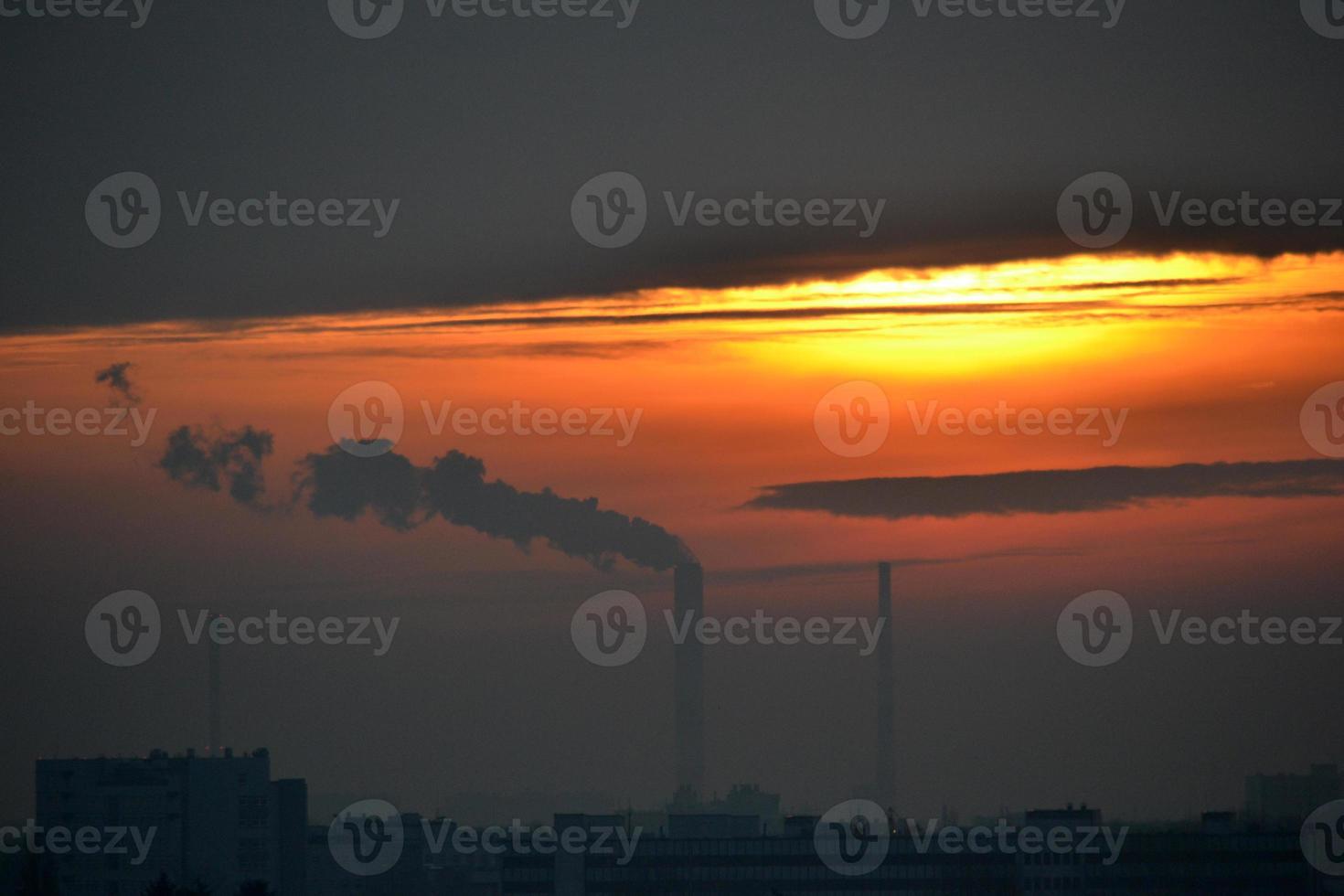 fumaça saindo da chaminé da fábrica ao pôr do sol foto