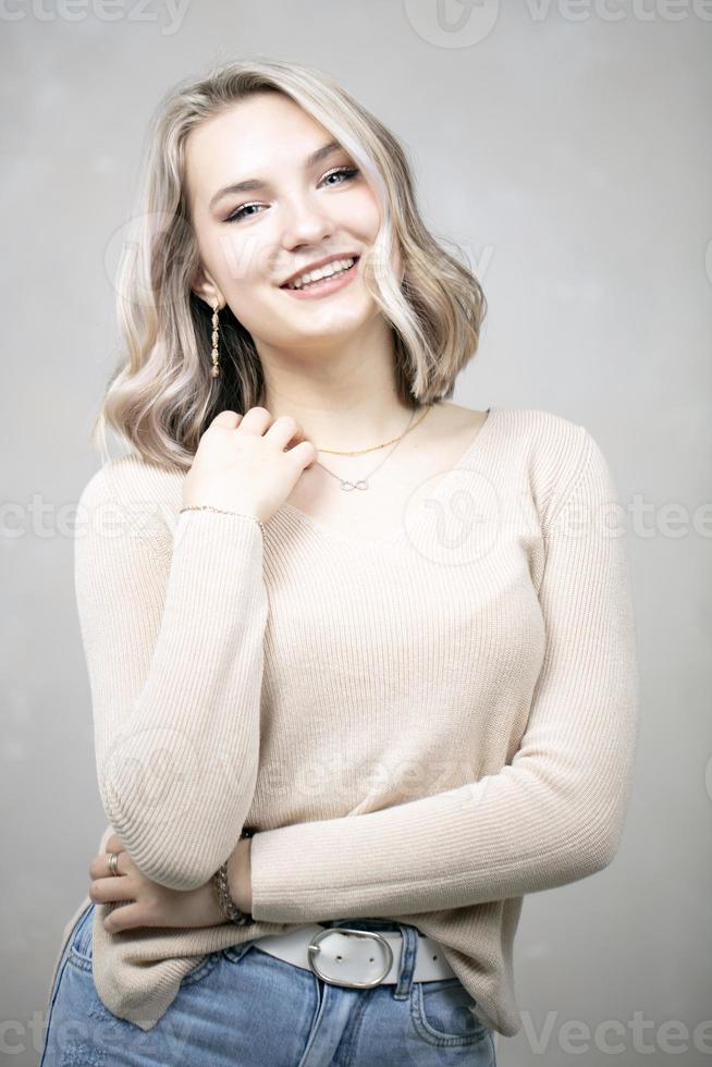 uma linda jovem com cabelos loiros e olhos azuis olha para a câmera e sorri. foto