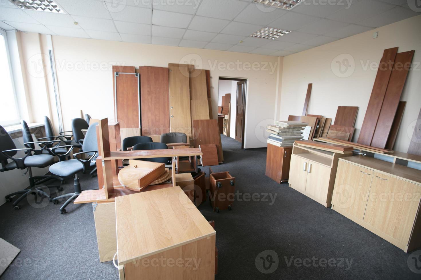 muitos móveis de escritório desmontados e espalhados em uma sala vazia. foto