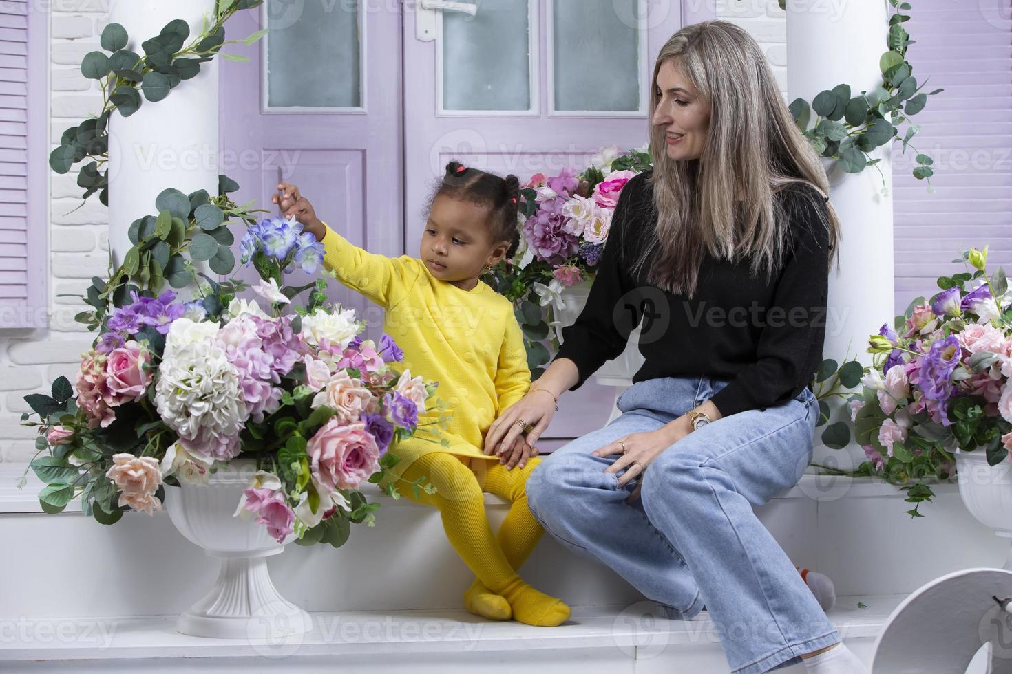 filha e mãe multiétnica estão sentadas na varanda da casa. mãe alegre com filha de nacionalidade africana. família de diferentes raças. foto