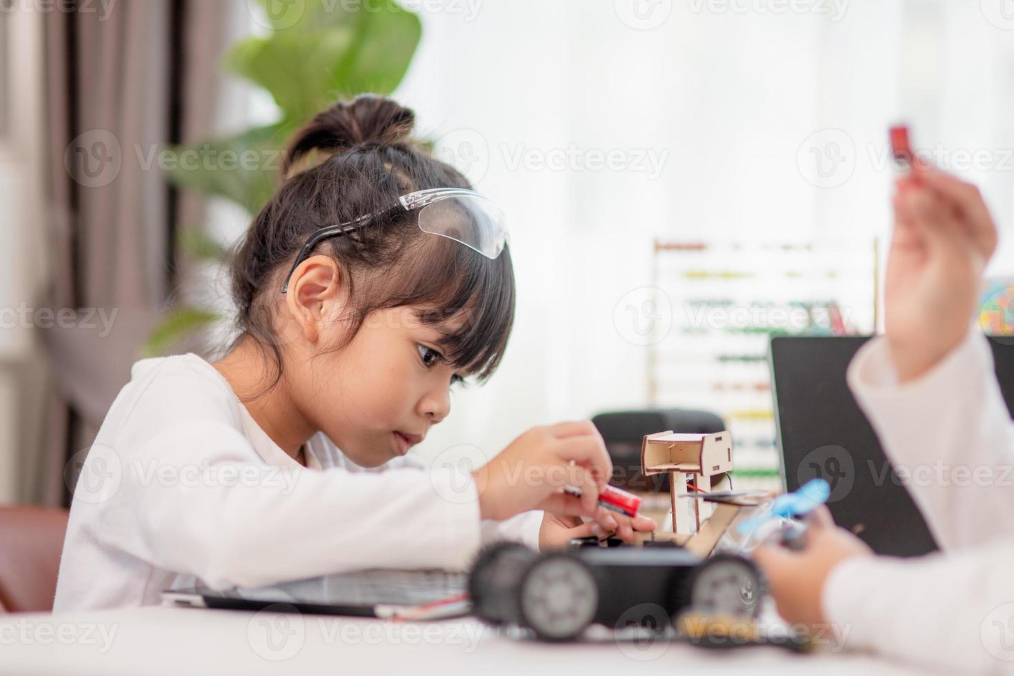 os alunos da ásia aprendem em casa na codificação de carros robóticos e cabos de placa eletrônica em haste, vapor, código de computador de tecnologia de ciência de engenharia matemática em robótica para o conceito de crianças. foto